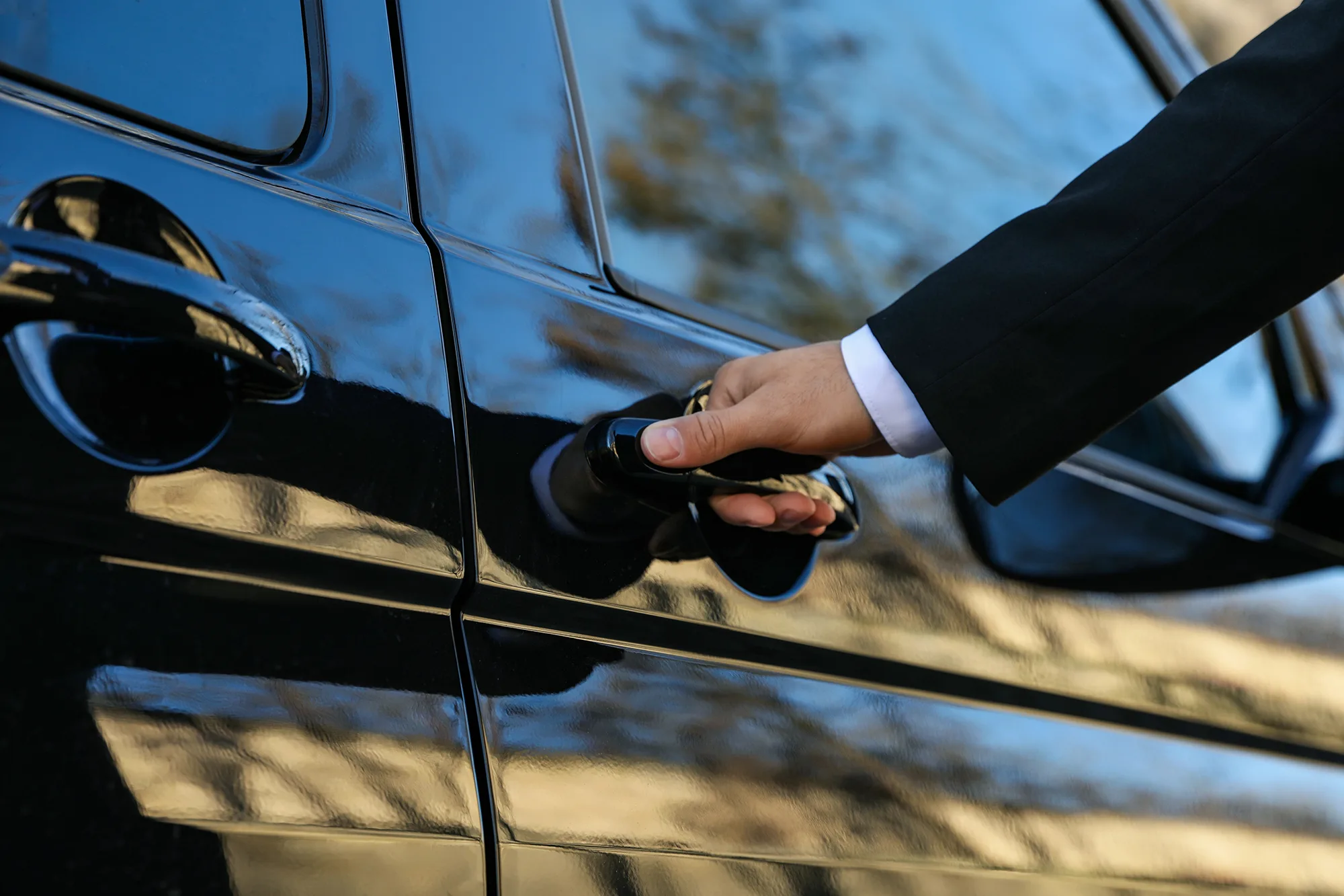 Private chauffeur opens car door for passenger